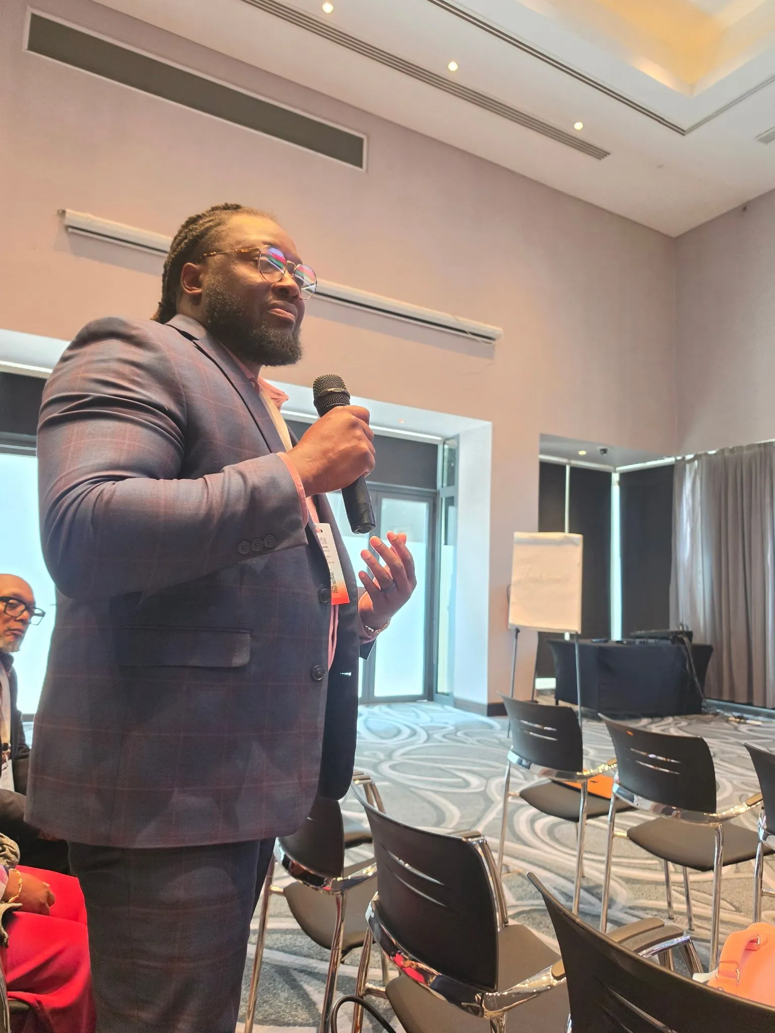 Maurice speaking into a microphone to a room of conference attendees